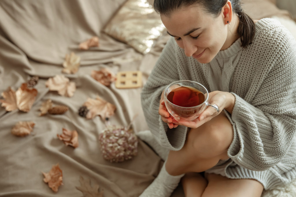 jeune femme avec une tasse de thé assise dans un lit